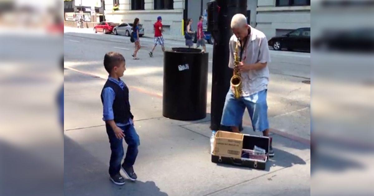Un niño baila espontáneamente con un músico callejero