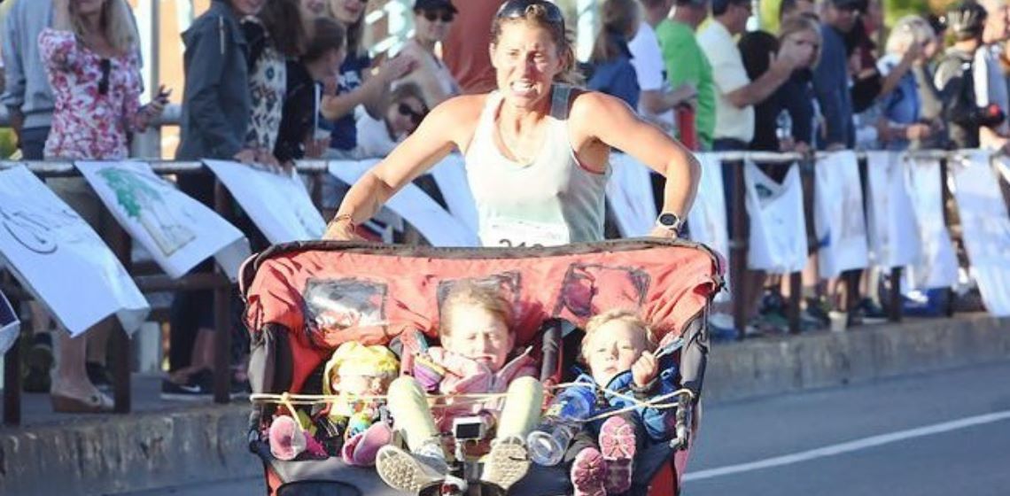 Mujer gana maratón al correr empujando una carriola con sus tres hijos