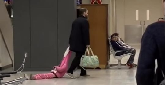 Padre frustrado arrastra a su hija por la capucha de su suéter a través del aeropuerto