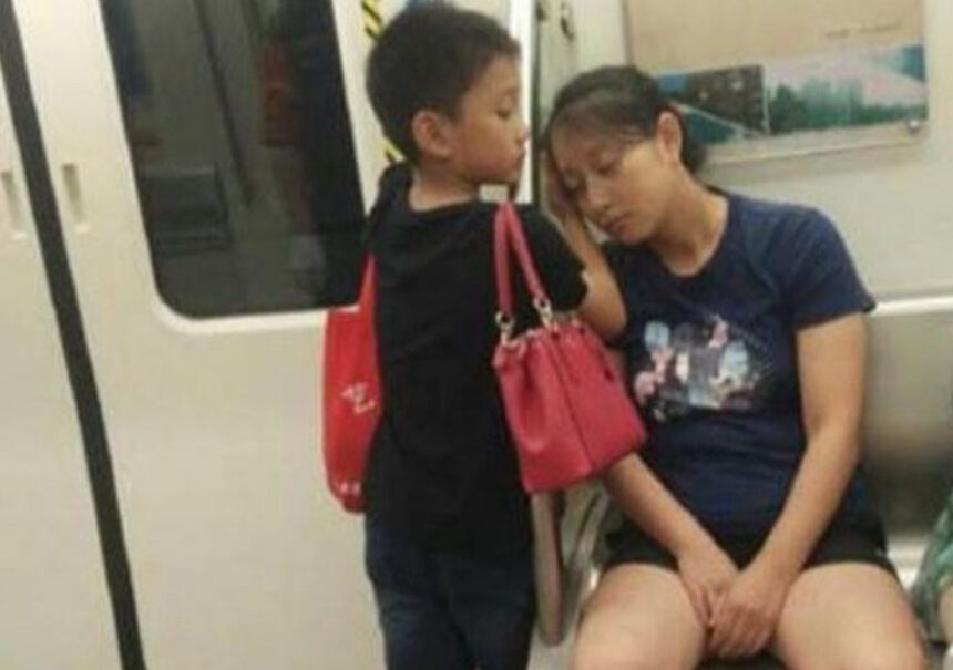 Mamá exhausta duerme en el tren: su hijo pone las manos bajo su cabeza y hacerle de almohada